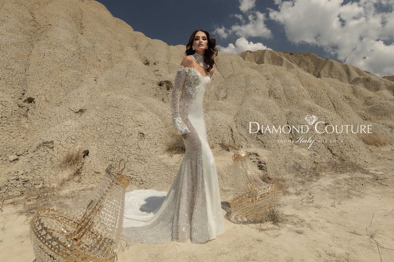 Abito da sposa Diamond Couture 2027: a figura intera, sirena con strascico e sovragonna scintillante, tra i calanchi del deserto